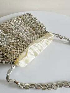 Close-up view of a chic silver metallic beaded shoulder bag with soft satin lining.