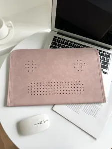 Pink leather laptop sleeve detail with breathable ventilation holes on a clean white desk.