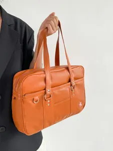 Detail shot of the brown PU leather JK uniform bag showcasing its smooth texture and double handles.