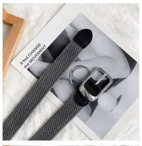 Close-up view of gray woven belt featuring elastic strap and polished silver metal buckle.