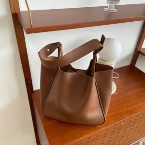 Detailed view of a stylish brown retro shoulder tote bag showcased on a modern wooden shelf.