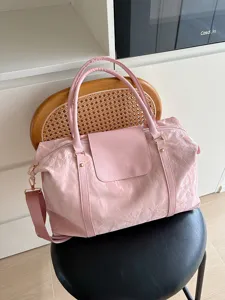 Gedetailleerd overzicht van de roze glanzende gekreukte reistas met voorflap en handvatten.