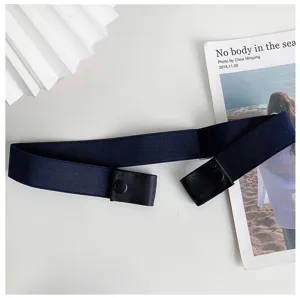 Detail view of dark blue elastic buckle-free belt on white background with minimalist card.