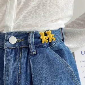 Gros plan détail de charmants clips de serrage de taille d'ours jaune pour jeans, accessoire.