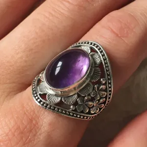 Primo piano dettagliato dell'anello in argento antico con ametista e motivo floreale.