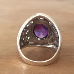 Primo piano dettagliato dell'anello in argento vintage con pietra viola e intaglio.