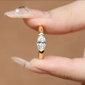 Stiloso anello minimalista con zircone taglio marquise e raffinata fascia in lega dorata.