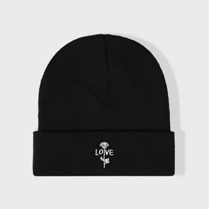 Gros plan détaillé du bonnet en tricot noir mettant en valeur la broderie rose blanche LOVE.