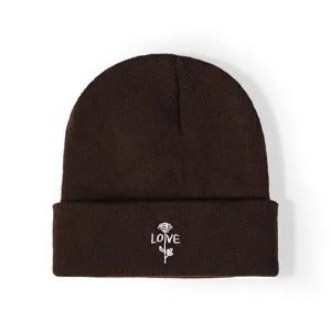 Bonnet en tricot marron foncé avec broderie délicate de rose blanche et texte love.