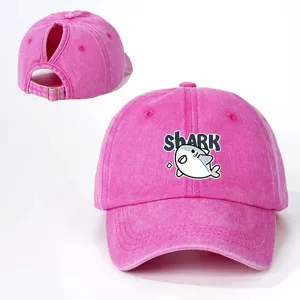 Primo piano del cappello da baseball rosa con coda di cavallo, grafico di squalo e cinturino.