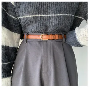 Dettaglio in primo piano di una sottile cintura in pelle marrone indossata con stile.