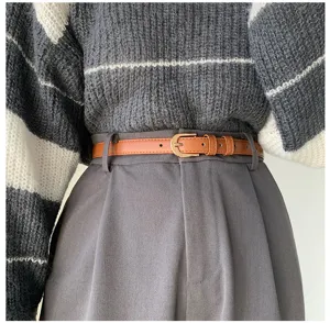 Dettaglio cintura sottile in pelle marrone da donna, accessorio elegante per pantaloni.