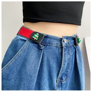 Detailed shot of a red elastic lazy belt with cute Christmas tree buckle on blue denim jeans.