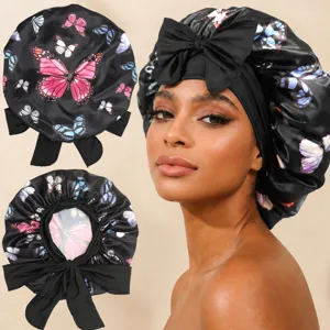 Silk satin sleep bonnet with butterfly print and long ribbon ties for hair care styling detail.