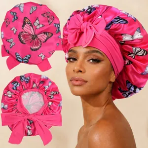 Pink satin sleep bonnet with butterfly print and ribbon tie for hair care and styling.