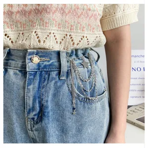 Detailed view of stylish star chain waist pin and brooch accessory on blue denim jeans.