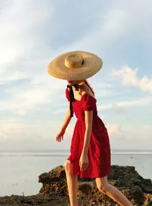Gros plan du chapeau de paille à large bord avec ruban noir dans un décor de plage.