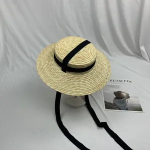 Chique platte stroohoed met zwarte linten en fijne textuur voor de zomervakantie.
