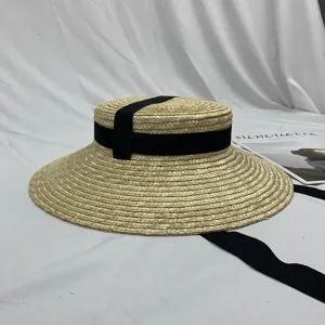 Detailopname van vintage platte strohoed met zwarte lintband en fijne natuurlijke textuur.