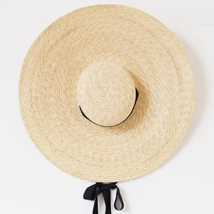 Chapeau de paille à bord extra large en détail, tressage raffiné et ruban noir pour l'été.