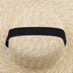 Vue détaillée du chapeau de soleil plat en paille surdimensionné avec ruban noir.