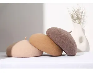 Close-up detail van zachte wollen mix baretten in neutrale tinten, gestyled met vaas.