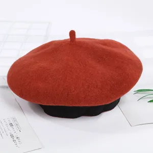 Primer plano detallado de la elegante boina de lana roja con borde acanalado negro clásico.