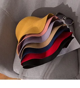 Detailed shot of multi-color wool felt bucket hats stacked on chair with sunglasses prop.
