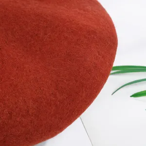 Primer plano detallado de una boina de fieltro de lana rojo óxido suave con textura fina.
