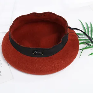 Vista detallada de boina de lana para mujer en rojo óxido, con banda y cinta negras.