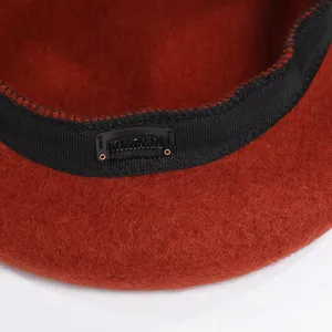 Detalle de boina de lana roja con banda interior negra y pinza para cabello antideslizante.