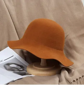 Detailed view of a caramel brown wool felt bucket hat on a wooden stand in a cozy autumn setting.