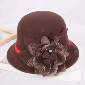Gros plan d'un élégant chapeau cloche en feutre de laine marron avec fleur et ruban rouge.