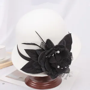 Élégant chapeau cloche blanc en laine pour femme avec une superbe décoration florale noire et plumes.