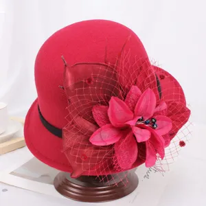 Vue détaillée de l'élégant chapeau cloche en laine rouge avec grande fleur et voile en filet.