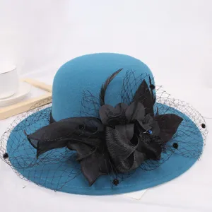 Close-up of elegant blue wool basin hat featuring delicate black mesh, floral and feather decor.