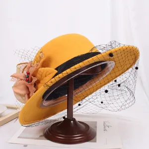 Detailed shot of yellow wool felt hat with black mesh veil and floral decor, elegant style.