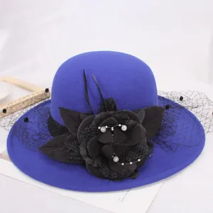 Close-up of elegant blue wool fedora hat featuring black floral and mesh veil detail.