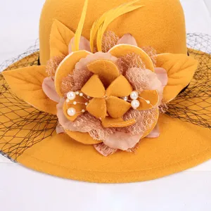Close-up of yellow wool felt hat detail, vintage flower, feather, and mesh veil decoration.