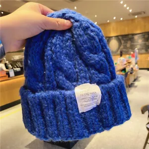 Gros plan sur le bonnet en tricot bleu roi, texture d'hiver douillette avec étiquette de marque.