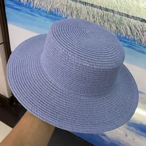 Détail du chapeau de paille bleu plat montrant la texture tissée fine pour la plage d'été.