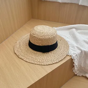 Gedetailleerd overzicht van de zomer raffia strohoed met zwarte lint, elegante zonnehoed.