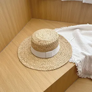 Gedetailleerd uitzicht zomer vrouwen raffia platte strohoed met wit lint, strand zonbescherming