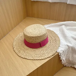 Gedetailleerd uitzicht op de chique strohoed met platte kroon en roze lint.