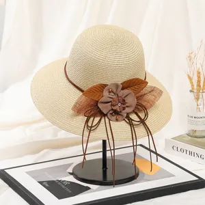 Detailansicht Damen Strohhut mit braunen Stoffblumen und eleganten Schleifenverzierung.