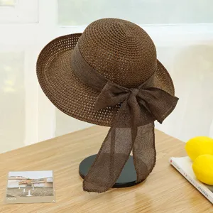 Detailed view of a stylish brown straw sun hat featuring a large elegant ribbon bow on side.