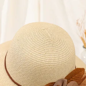Nahaufnahme Detail des Damen Sommer Strohhuts mit braunem Lederband und Blumendekor.