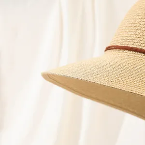 Nahaufnahme Detail Sommer Damen Strohhut Sonnenhut mit braunem Lederriemen am Strand.