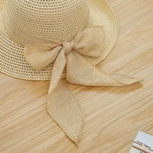 Detailed view of wide brim straw sun hat with stylish burlap bow for summer beach travel outdoor.