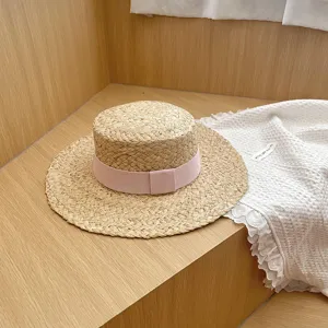 Close-up van het detail van de platte raffia strohoed met roze lint op houten achtergrond.
